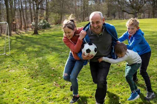 older man and two kids playing soccer