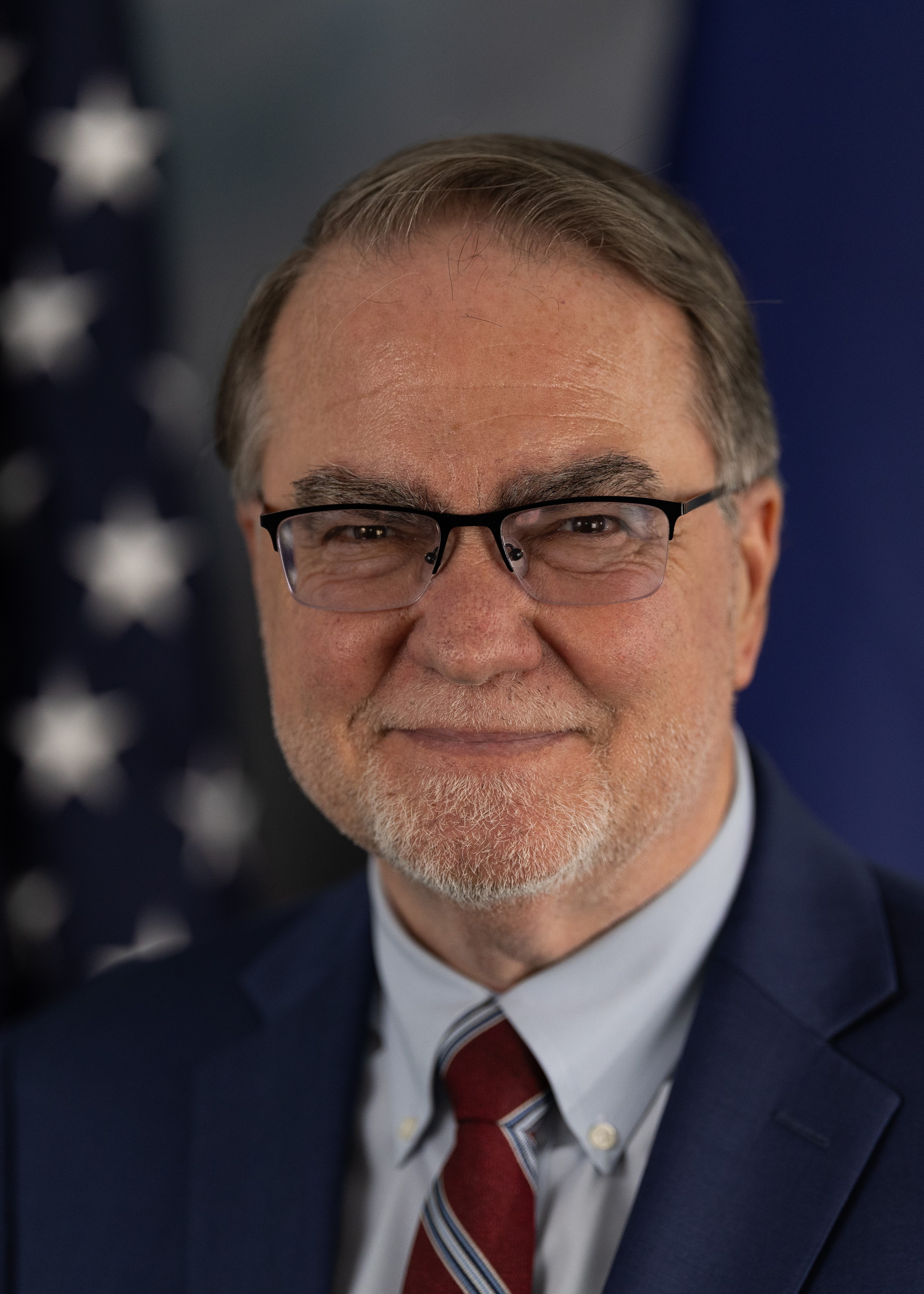 Headshot of Commissioner Langefeld infront of a flag